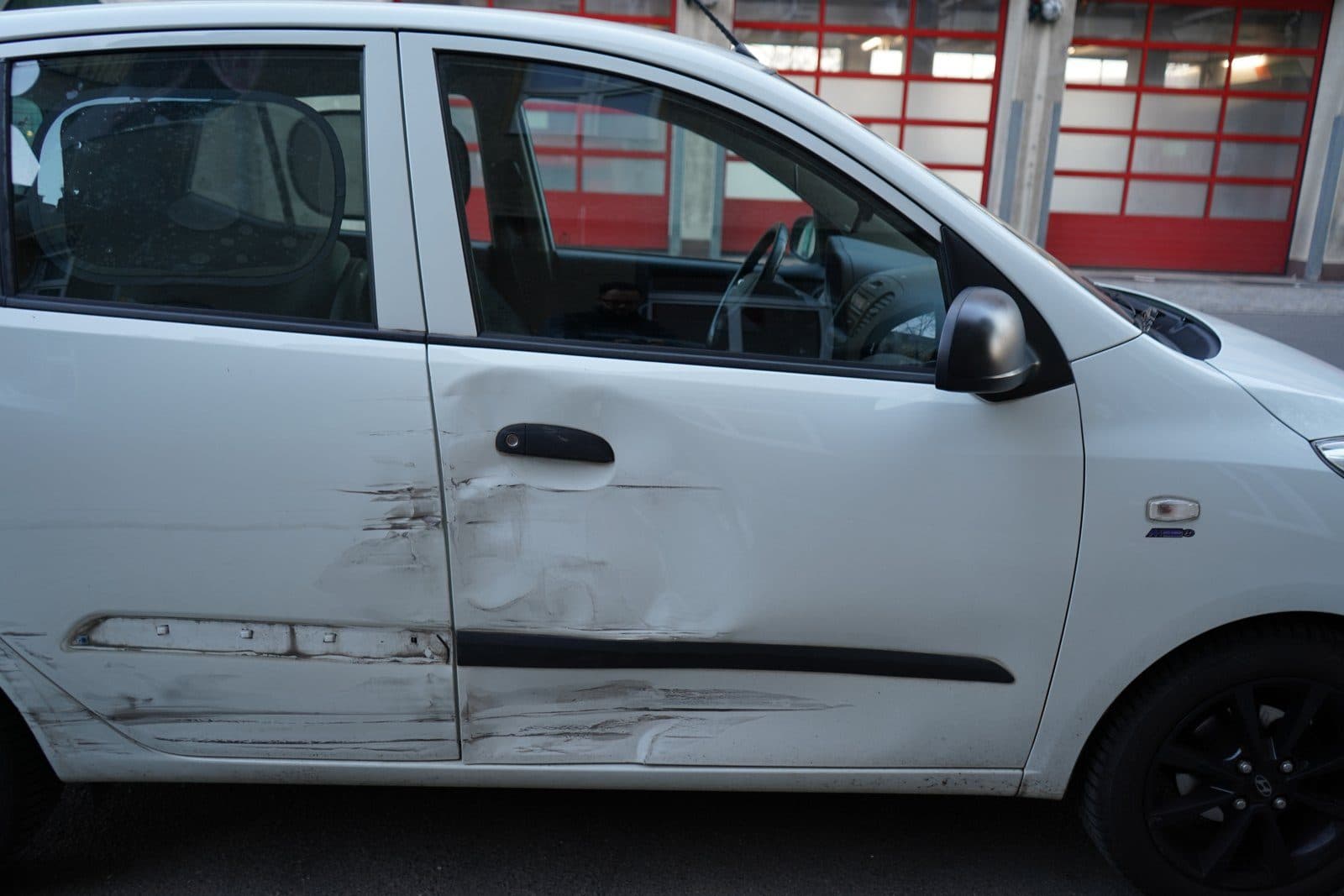 Weißer Hyundai i10 von der Seite, beide rechten Türen beschädigt