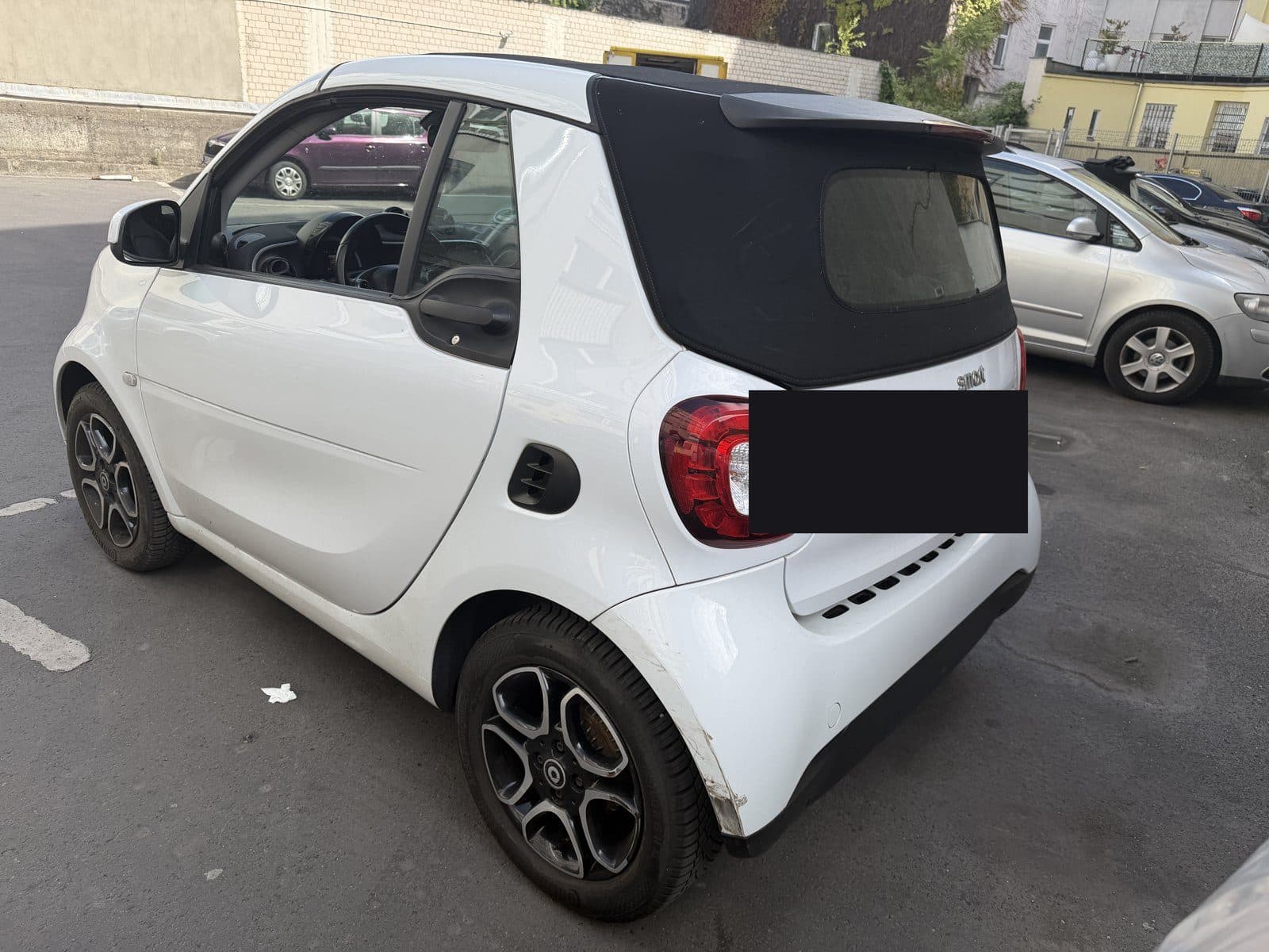 Weißes Smart Cabrio mit Schaden hinten links, Kennzeichen abgedeckt
