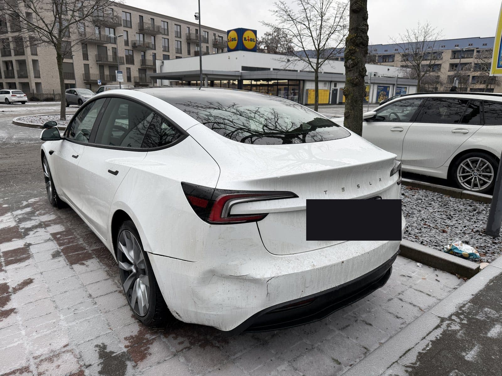 Weißer Tesla mit Heckschaden links, Kennzeichen abgedeckt